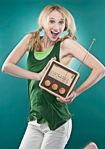 拿着棕色晶体管收音机的微笑女人
